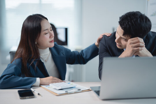 Asian businesspeople comforting each other after a bad news in office, businesswoman consoling sad businessman after he made mistake at work