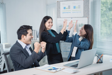 Asian business team celebrating success in an office meeting, excited entrepreneurs giving high fives after signing a profitable contract, showcasing teamwork and collaboration