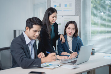 Group of asian businesspeople working together using laptop, discussing and analyzing data in the...
