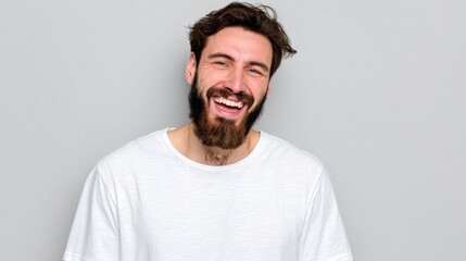 Man with a beard is smiling and wearing a white shirt. He looks happy and content. Concept of warmth and positivity