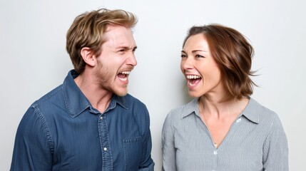 Obraz premium Man and woman are laughing and smiling at each other. The man is wearing a blue shirt and the woman is wearing a white shirt