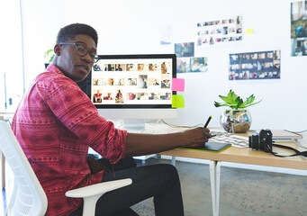 Graphic tablet stylus hovering above desk in creative office, with DSLR camera and reference prints