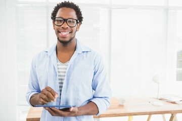 African American man holding tablet and smiling in bright workspace with wooden desk and coffee mug