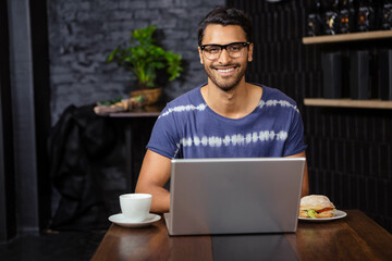 Laptop sitting on wooden table at casual cafe interior, with coffee cup and sandwich © WavebreakMediaMicro