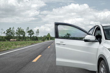 A white vehicle with an open door in side of the road. The driver is needing for help or giving assistance for example.