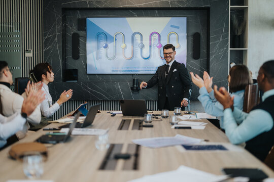 A diverse group of business people applauding during a meeting. The presenter stands by a large screen displaying a graph. The scene conveys teamwork and positive workplace dynamics.