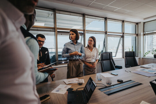 A multicultural group of business people engaged in a meeting within a modern office setting, discussing strategies and plans. The environment reflects teamwork and collaboration among colleagues.