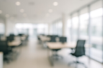 A blurred view of an office space with desks chairs and large windows letting in soft natural light inside