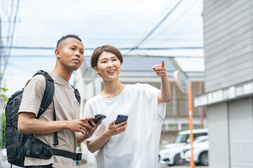 スマホを持って黒人男性に道案内する日本人女性