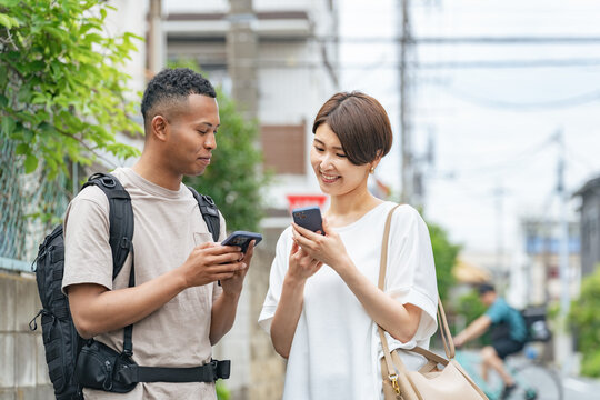 A Japanese woman conversing with a black man using a smartphone translation app