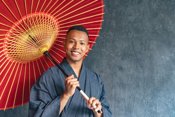 A black man wearing a Japanese yukata and holding a Japanese umbrella