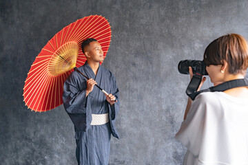 A black man wearing a yukata being photographed by a photographer
