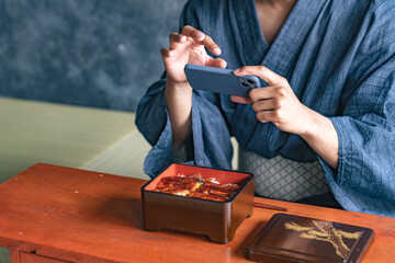 A black man taking a photo of eel rice bowl at a Japanese restaurant
