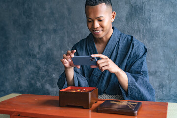 日本料理店で鰻重の写真を撮る黒人男性