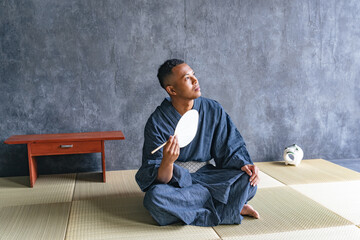 A black man wearing a Japanese yukata relaxing on a tatami mat
