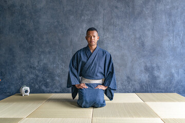 A black man wearing a yukata sitting on a tatami mat