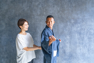 A black man having a Japanese kimono dresser help him put on a yukata