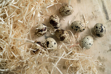 Still life with quail eggs surrounded by straw from above
