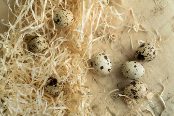 quail eggs scattered on a wooden surface surrounded by straw