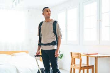 Black male traveler standing with suitcase in hotel room