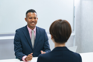 A Japanese female staff member interviewing a black male businessman