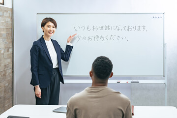 黒人男性に日本語学校でビジネス用語を教える女性教師