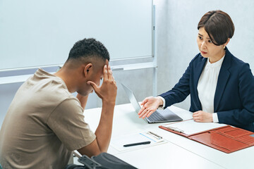 悩む黒人男性と面談する日本人女性スタッフ