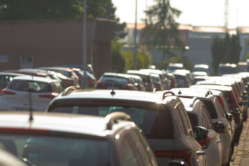 Numerous cars are parked along the entire side of the road today