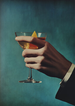 male hand holding cocktail wearing suit in vintage 1960s color film photo with blue background