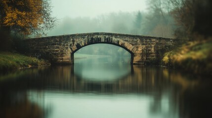 Fototapeta premium Serene stone bridge over misty river in rural landscape