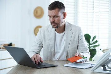 Travel agent with passports and tickets at wooden table in office