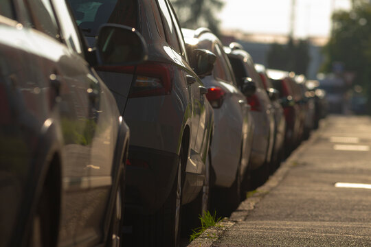 A long row of various cars is neatly parked along the side of the busy road, creating an organized scene of parked vehicles