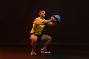 Man exercising with medicine ball on black background