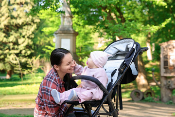 Mother with her cute baby in stroller at park