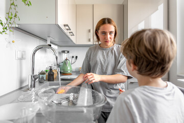 Fototapeta premium Teenage girl washing dishes. Washing dishes in the kitchen. Housework.