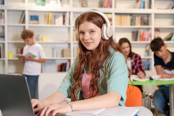 Student with laptop studying at table in library