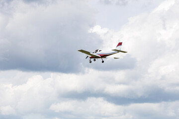 Light aircraft flying in mid-air against a background of dramatic clouds. General aviation concept, transportation, private flight.