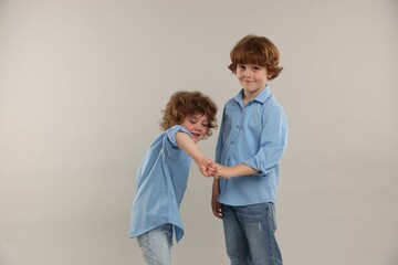 Cute little brothers bumping fists on light background