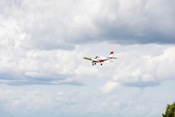 Light aircraft flying in mid-air against a background of dramatic clouds. General aviation concept,...