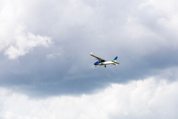 Light aircraft flying in mid-air against a background of dramatic clouds. General aviation concept, transportation, private flight.