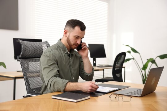 Man talking on phone while working at desk in office
