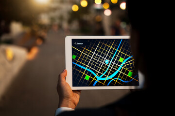 User checking digital map on tablet while walking in night street