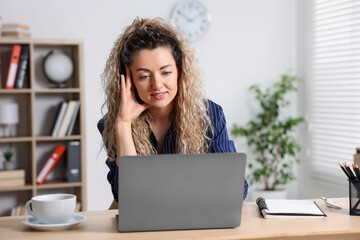 Woman working with laptop at desk in home office