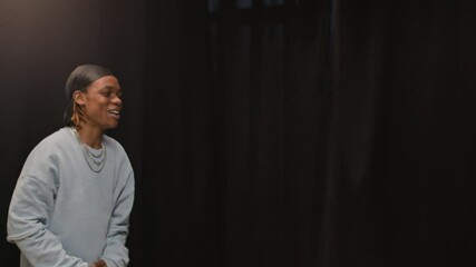 Medium shot of charismatic young African American male performer getting on stage and introducing himself participating in audition or talent show