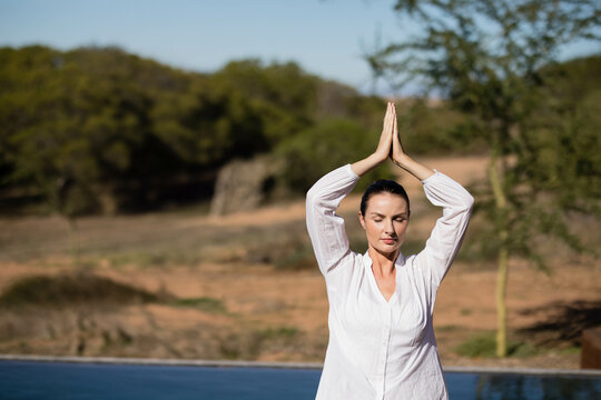 Female standing at edge of rectangular pool outdoors, surveying sunlit rural hills under clear sky