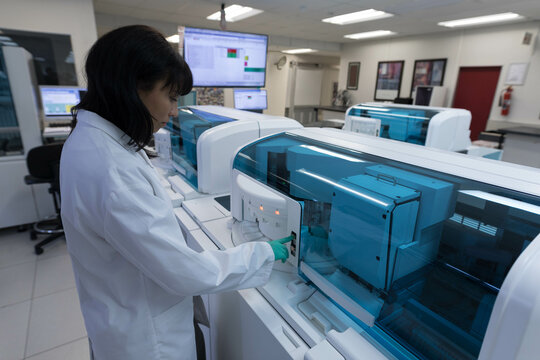 Automated clinical analyzers operating on central lab bench, with blue covers and monitor display