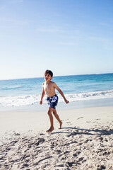 Naklejka premium Gentle ocean waves lapping onto beige sand along beach under clear sky with footprints, copy space