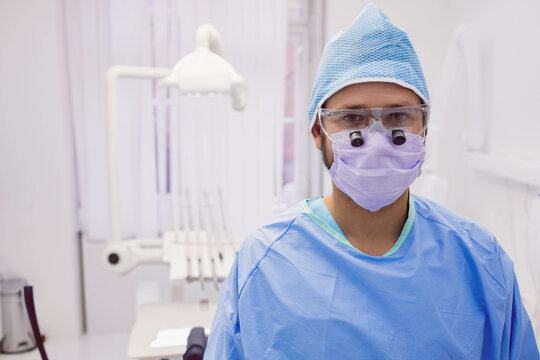 Instrument tray holding handpieces and probes beside white dental chair receiving lamp illumination