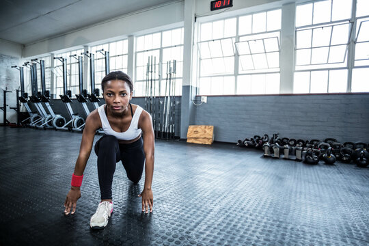 African American woman in sportswear lunging in gym using kettlebells, barbells, plyo box, clock