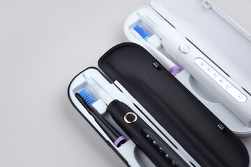 Modern electric ultrasonic toothbrush with rechargeable battery on a gray surface.